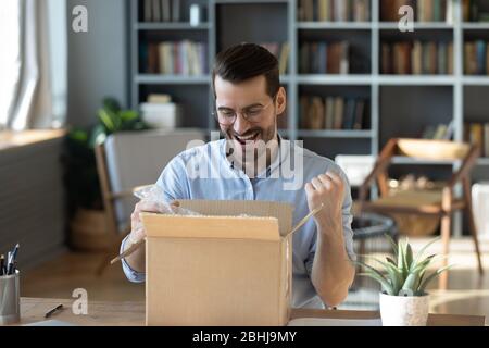 Excited happy man looking into cardboard box, receive parcel Stock Photo