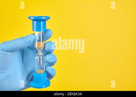 Dentist holding sand glass on yellow background. Copy space