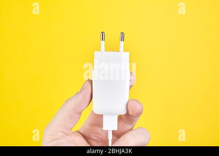 Male hand holding ac dc adapters smartphone recharge supply. Close up Stock Photo