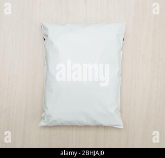 Blank white plastic bag package mockup template on wooden background. Stock Photo