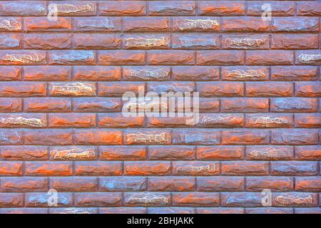 The stone wall of smooth rectangular bricks is covered with red and blue paint. Stock Photo