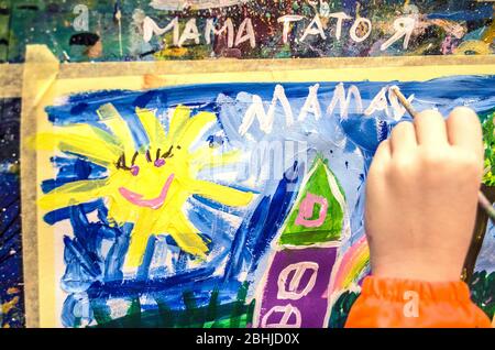 Children's drawing fairy-tale city houses and the sun for mom. Mom's day concept photo. Baby's hand writes mom. Stock Photo
