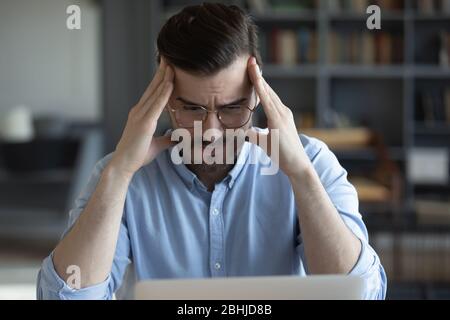 Unhappy tired businessman touching temples, working on difficult task Stock Photo