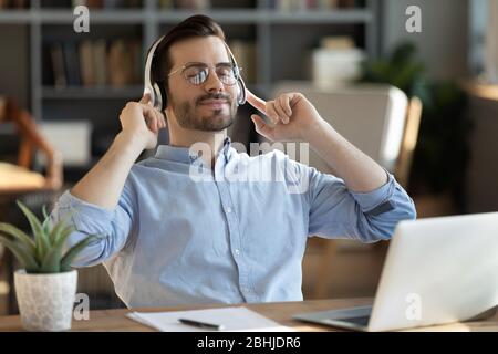 Peaceful satisfied man wearing headphones enjoying favorite music Stock Photo