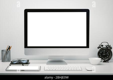Stylish workspace with blank screen computer display and tablet for mockup on work desk with keyboard, mouse, clock, eyeglasses and stationery. Stock Photo