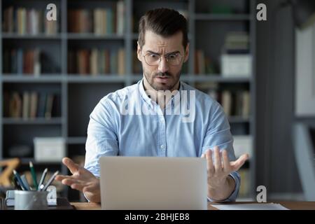 Unhappy shocked man having problem with laptop, looking at screen Stock Photo