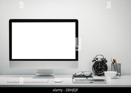 Stylish workspace with blank screen computer display and tablet for mockup on work desk with keyboard, mouse, clock, eyeglasses and stationery. Stock Photo