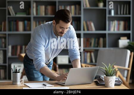 Confident businessman wearing glasses standing at desk, working online Stock Photo