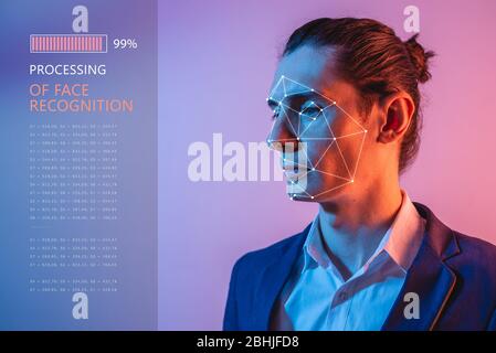 Recognition of a male face by layering a mesh and the calculation of the personal data by the software in neon light. Biometric verification and ident Stock Photo