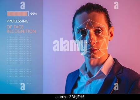 Recognition of a male face by layering a mesh and the calculation of the personal data by the software in neon light. Biometric verification and ident Stock Photo