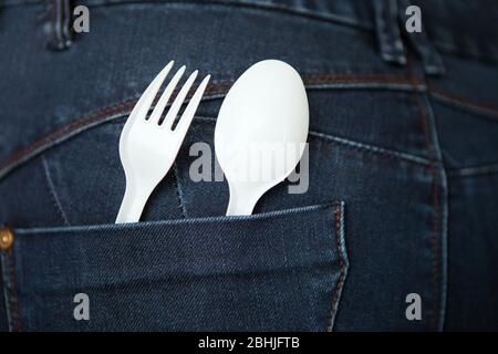 Take Out Food Concept with blue Denim Jeans with a white Fork and Spoon in the Pocket. reusable plastic spoon and fork at the pocket. safe environment Stock Photo