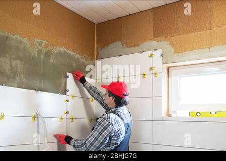 A worker installs ceramic tiles, building a house Stock Photo