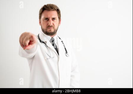 Portrait of male doctor with stethoscope in medical uniform pointing her finger posing on a white isolated background Stock Photo