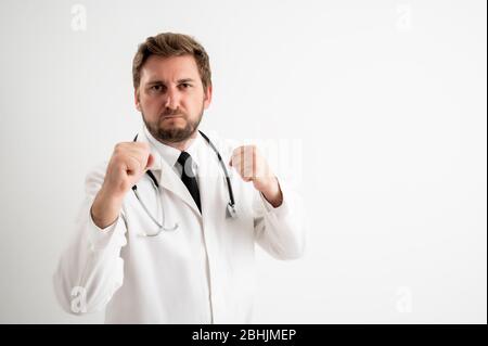 Portrait of male doctor with stethoscope in medical uniform showing fists, boxing posing on a white isolated background Stock Photo