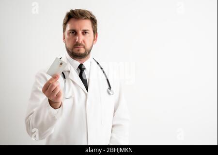 Portrait of male doctor with stethoscope in medical uniform showing card posing on a white isolated background Stock Photo