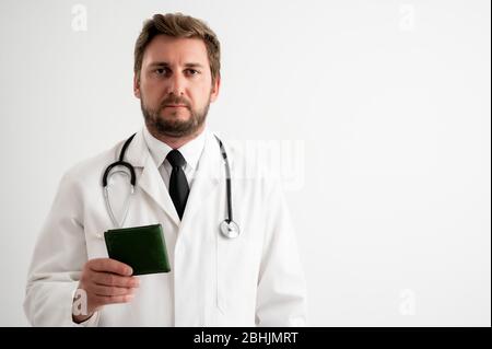 Portrait of male doctor with stethoscope in medical uniform showing his wallet posing on a white isolated background.