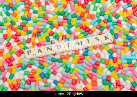 Multicoloured pills caplets & letter tiles: PANDEMISK - Swedish & Norwegian adjective for Pandemic. Coronavirus conceptual, CV19 / Covid 19 metaphor. Stock Photo