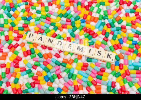 Multicoloured pills caplets and letter tiles: PANDEMISK - Swedish & Norwegian adjective for Pandemic. Coronavirus conceptual, CV19 / Covid 19 metaphor Stock Photo