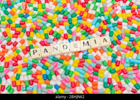 Multicoloured pills caplets and letter tiles: PANDEMIA - Spanish, Italian & Polish noun for Pandemic. Coronavirus conceptual, Covid 19 / CV19 metaphor Stock Photo