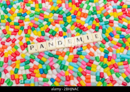 Multicoloured pills caplets & letter tiles: PANDEMIE - German, French, and Dutch & Czech (Noun) word for Pandemic. CV19 / Coronavirus conceptual. Stock Photo