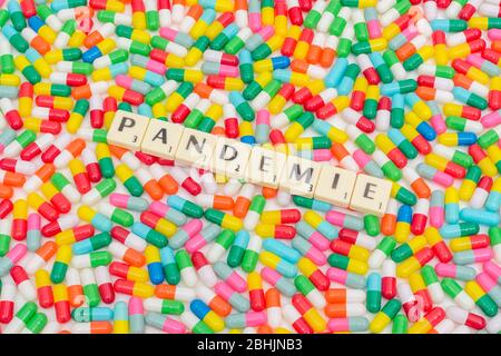 Multicoloured pills caplets and letter tiles: PANDEMIE - German, French, and Dutch & Czech (Noun) word for Pandemic. Coronavirus conceptual. Stock Photo