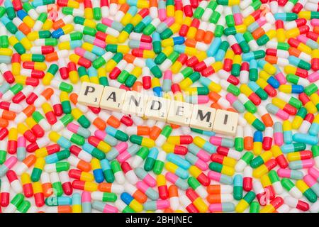 Multicoloured pills caplets & letter tiles: PANDEMI - Swedish & Norwegian noun for Pandemic. Also Danish word for Pandemic. Coronavirus / CV19 concept Stock Photo