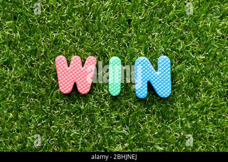 Toy foam letter in word win on green grass background Stock Photo