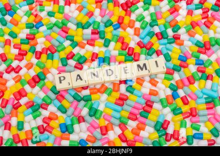 Multicoloured pills caplets & letter tiles: PANDEMI - Swedish & Norwegian noun for Pandemic. Also Danish word for Pandemic. Coronavirus / CV19 concept Stock Photo