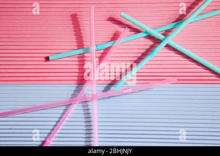 Colorful drinking straws on a pink and blue background, without a plastic Cup. Colorful summer background with Sunny shadows.Top view. Stock Photo