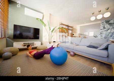 woman practicing yoga in her apartment in front of the window Stock Photo