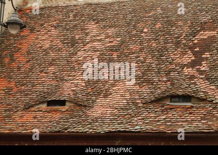 Eye-like attic windows and roof of traditional old house in Sibiu, Romania Stock Photo