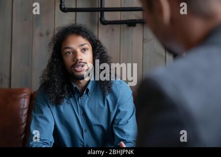 African American man having conversation with friend in cafe Stock Photo