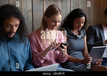 Multiracial young people relax on sofa using devices Stock Photo