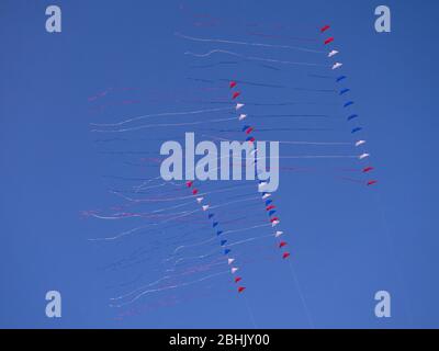 Stack of red, white an blue dual line stunt kites on a blue sky ...