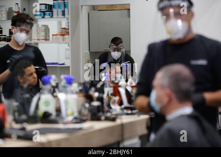 Modin, Israel. 26th April, 2020. Israeli barbers wearing face masks work in a barber shop in central Israeli city of Modiin on April, 26, 2020. All street shops in Israel, including barber shops and beauty salons, have received approval from the government to reopen starting from Saturday evening. (Photo by Gil Cohen Magen/Xinhua) Stock Photo