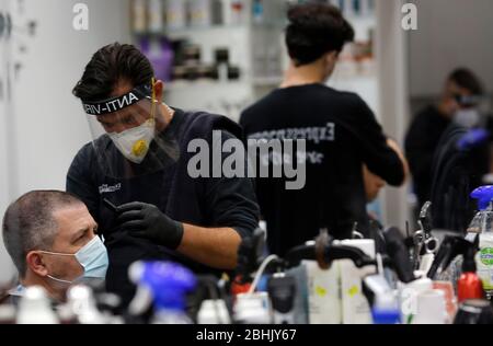 Modin, Israel. 26th April, 2020. Israeli barbers wearing face masks work in a barber shop in central Israeli city of Modiin on April, 26, 2020. All street shops in Israel, including barber shops and beauty salons, have received approval from the government to reopen starting from Saturday evening. (Photo by Gil Cohen Magen/Xinhua) Stock Photo