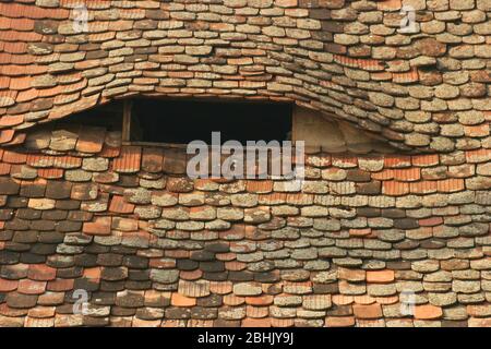 Eye-like air flow opening through the roof of traditional old house in Sibiu, Romania Stock Photo