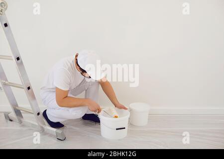 House painter in white uniform on a white background for painting in the room. Profession work painter. Stock Photo