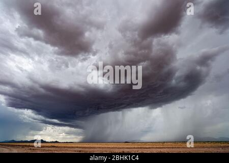 Storm clouds with heavy rain falling in the desert during the summer monsoon season near Chuichu, Arizona Stock Photo