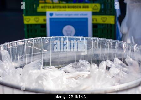 Outdoor trash bin full of used disposable wipes and plastic gloves at a supermarket to protect customers against coronavirus covid-19 infection. Stock Photo