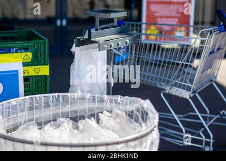 Trash bin full of used disposable wipes and plastic gloves at entrance of a supermarket to protect customers against coronavirus covid-19 infection Stock Photo