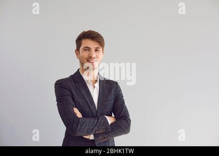 Smiling man crossed his arms in a casual jacket on a gray background. Stock Photo