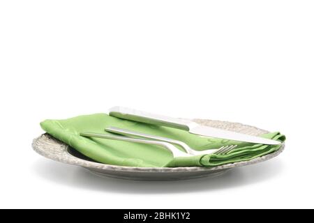 Ornate metal plate and a brushed silver flatware set photographed on a white background with ample copy space. Stock Photo