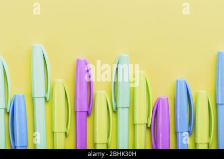 Multi-colored pens on a yellow background with free space. Minimalistic concept Stock Photo