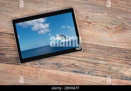 Cruise ship on screen of digital tablet. Top view of mobile pc device on old wooden table. Cruise travel and travel agency sales concept. Stock Photo