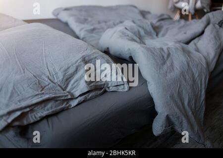 Closeup of gray pillows and blankets with a sheet on the bed Stock Photo
