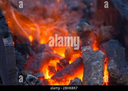 blacksmith furnace with burning coals, tools, and glowing hot metal workpieces Stock Photo