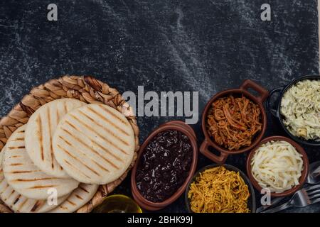 Top view of woven basket filled with a group of Latin American arepas on a dark background, the image has a space to place texts and logos Stock Photo