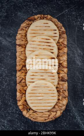 Top view of woven basket filled with a group of Latin American arepas on a dark background Stock Photo