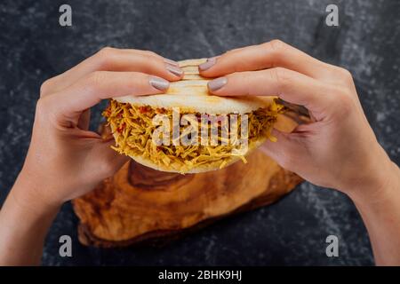 Woman holding a chicken arepa typical of Latin American cuisine. Stock Photo